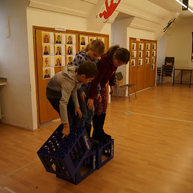 Kinder stehen auf leeren Getränkekisten