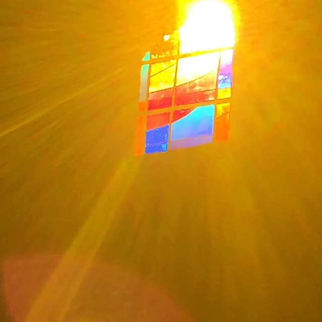 Fenster der Dorfkapelle durch das die Sonne in Gelb strahlt