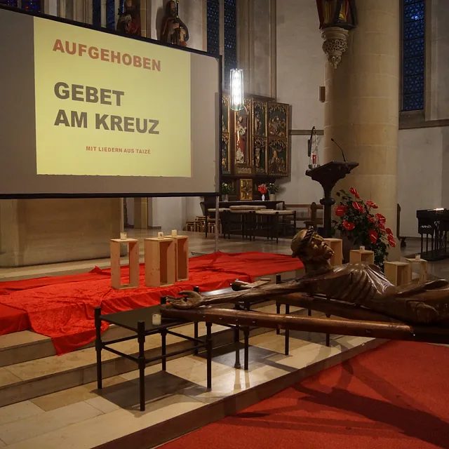 Das Coesfelder Kreuz vor dem dekorierten Altarraum, im Hintergrund die Leinwand für die Liedertexte