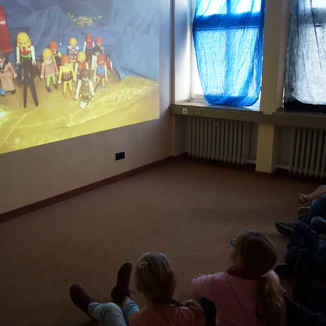 Präsentation an der Wand, im Vordergund Kinder