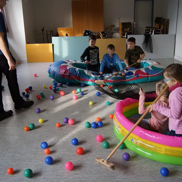 DIe Kinder in den Schlauchbooten versuchen Plastikbälle für eine Fisch WM zu sammeln