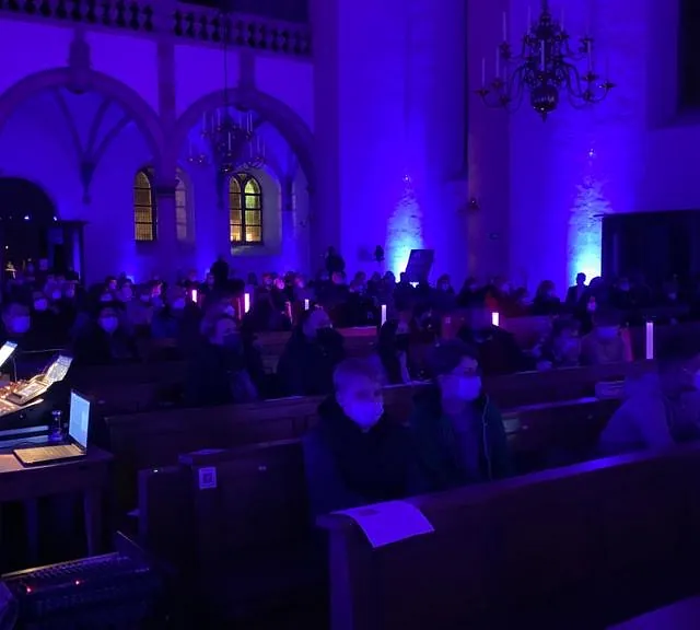 Gemeindemitglieder in blau beleuchteter Kirche