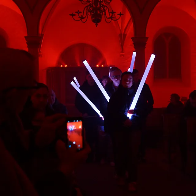Jugendliche mit Lichtsäulen in rot beleuchteter Kirche.